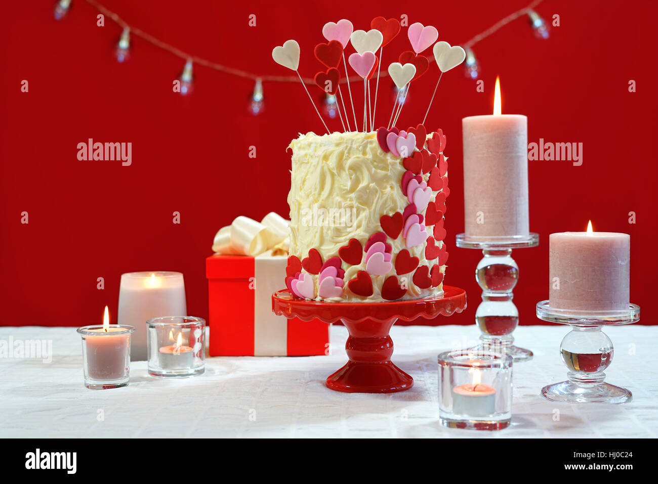 Belle St Valentines Day party table avec showstopper rouge, blanc et coeurs roses gâteau double couche, avec glaçage au chocolat blanc. Banque D'Images