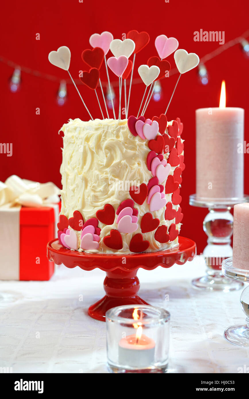 Belle St Valentines Day party table avec showstopper rouge, blanc et coeurs roses gâteau double couche, avec glaçage au chocolat blanc. Banque D'Images