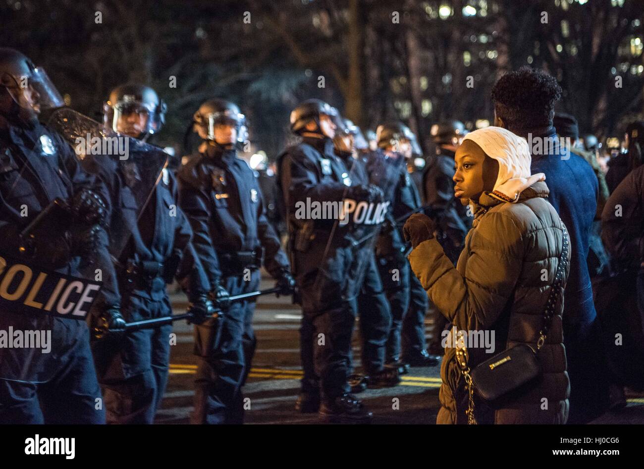 Manifestants à l'investiture du président Donald Trump à Washington DC. Une jeune femme noire et son partenaire stand de défi, avec un poing levé, la solidarité fo en face de la police habillés en tenue de combat tactique. Banque D'Images