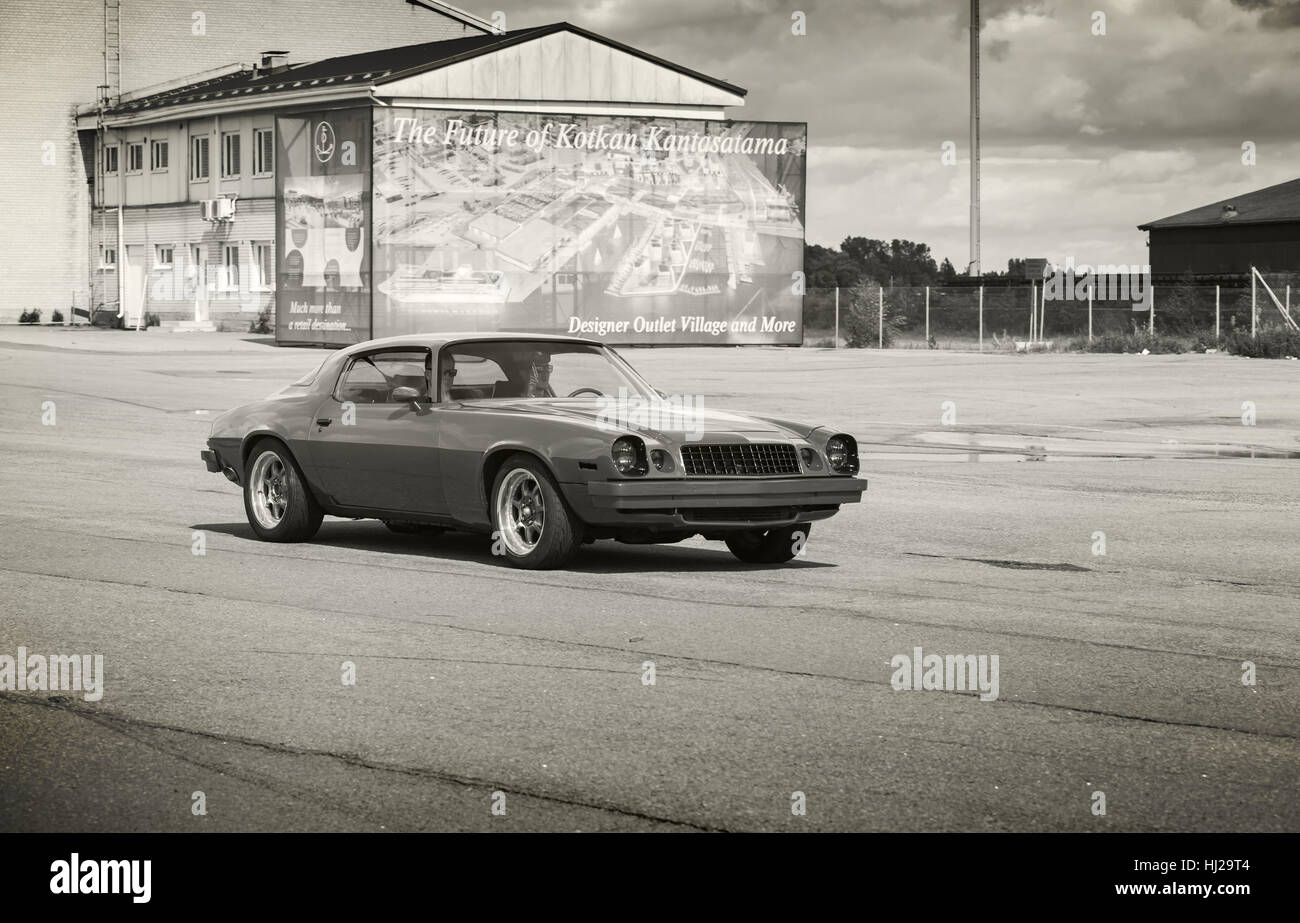 Kotka, Finlande - le 16 juillet 2016 : Chevrolet Camaro 1976 Rouge Sport va en bas de la rue dans la ville européenne, aux tons monochromes, photo retro style Banque D'Images