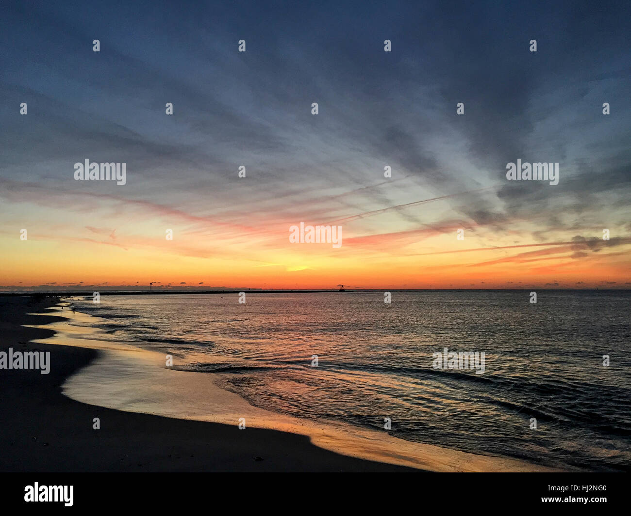Un cadre coloré et nuageux lever du soleil sur une plage de sable fin. Banque D'Images