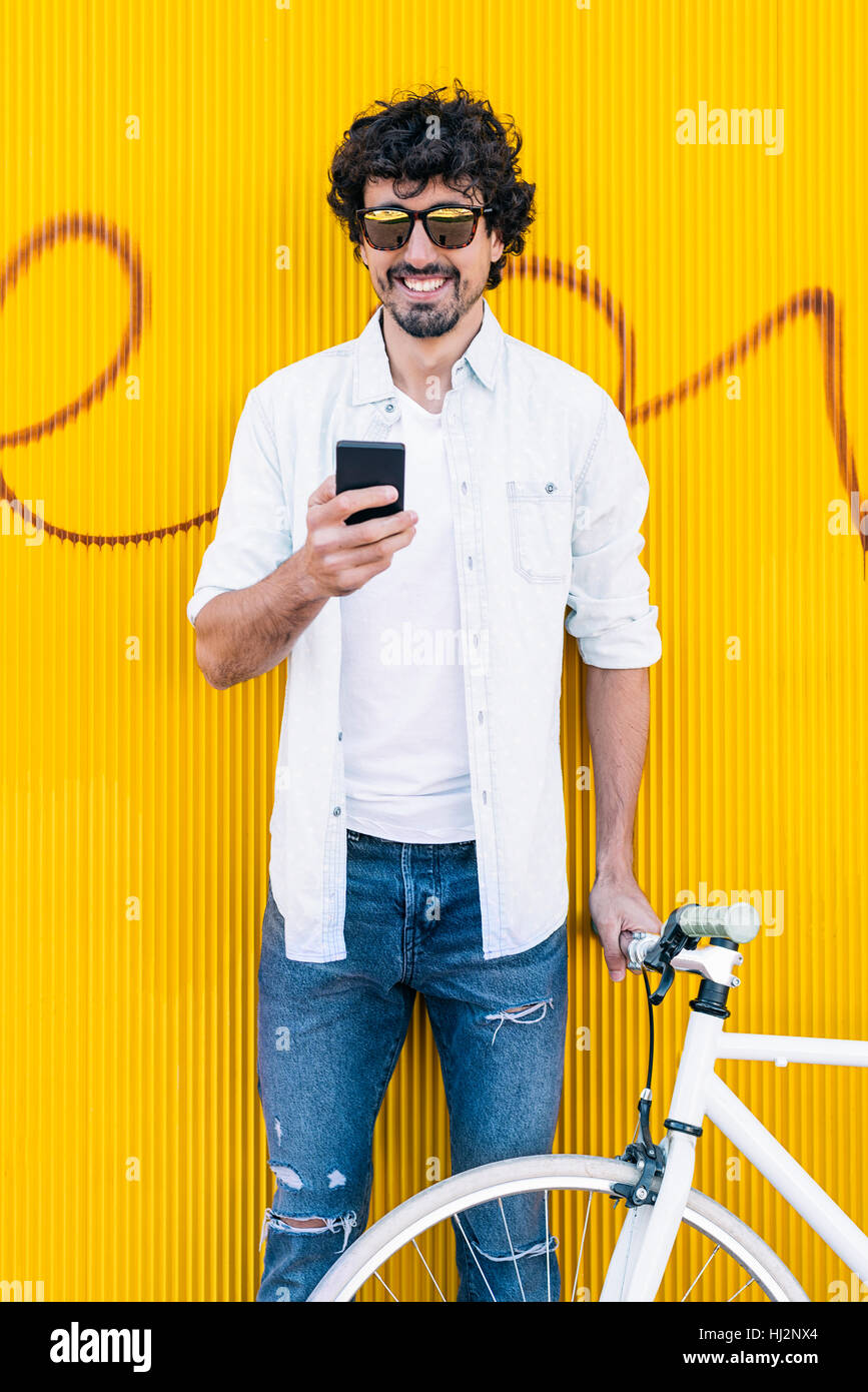 Utdoor portrait of handsome young man with mobile phone et location d'engins fixes dans la rue. Banque D'Images