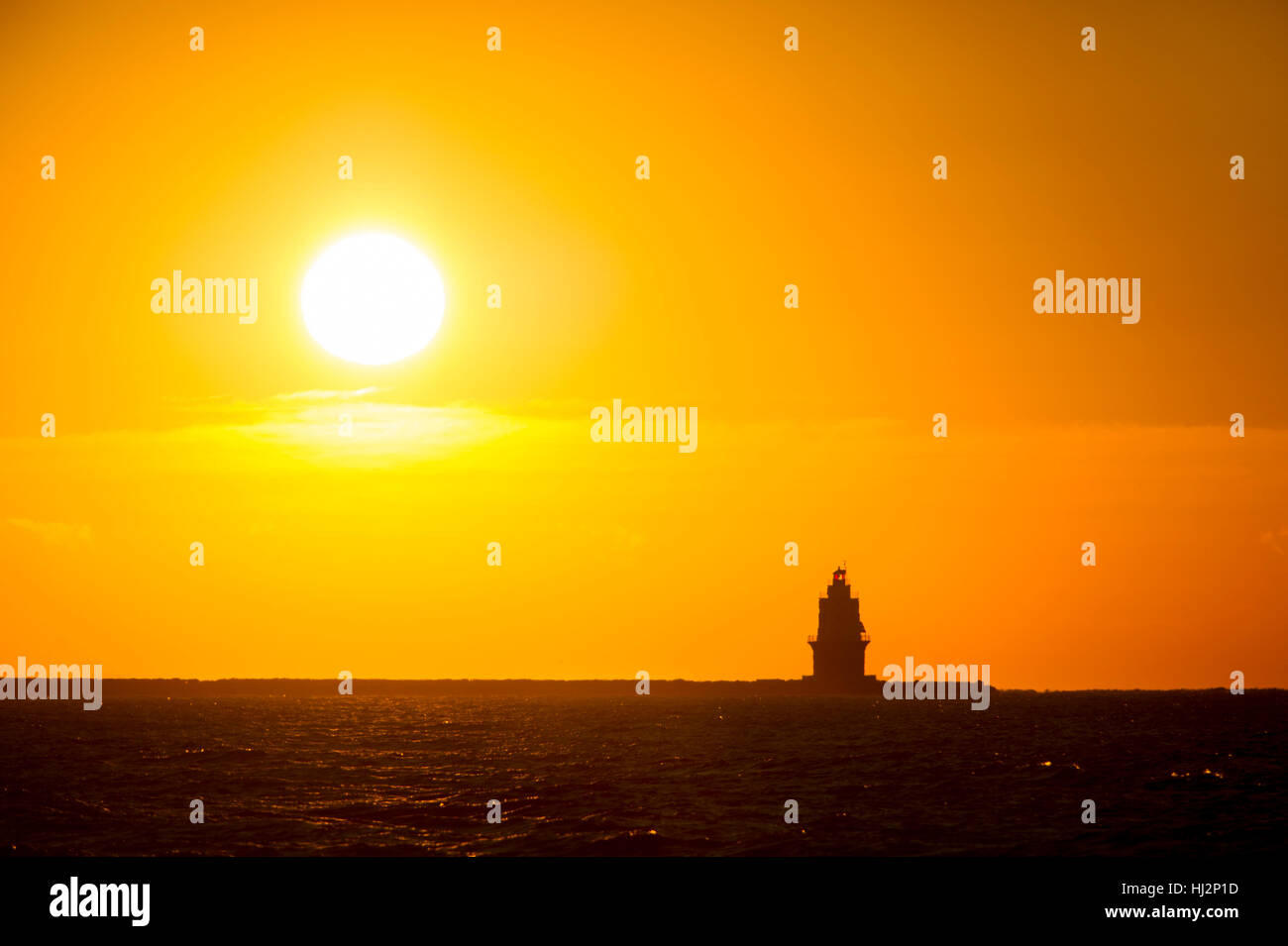 Le soleil se lève derrière la silhouette d'un phare dans l'océan Atlantique. Banque D'Images