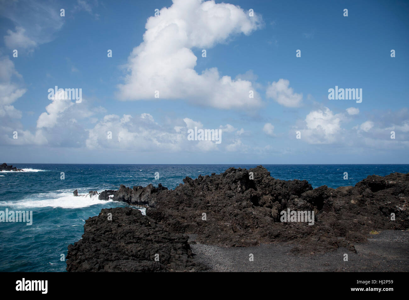 Un littoral volcanique rocheux avec les vagues de l'océan turquoise. Banque D'Images