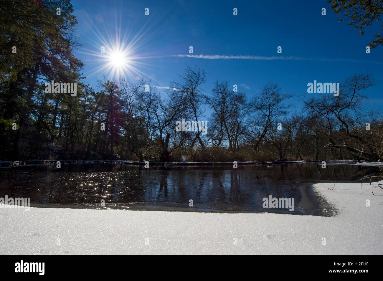 La plupart du temps une rivière gelée sur une froide journée d'hiver ensoleillée avec de la neige au premier plan. Banque D'Images