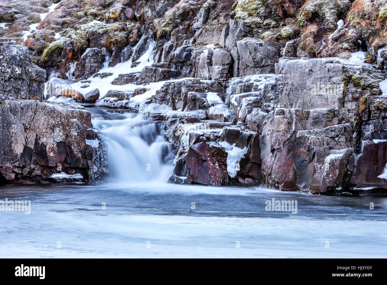 Une cascade entourée de glace et de neige dans les hautes terres d'Islande terrain encadrées paysage pittoresque vous propose le désert gelé incarnant. Banque D'Images