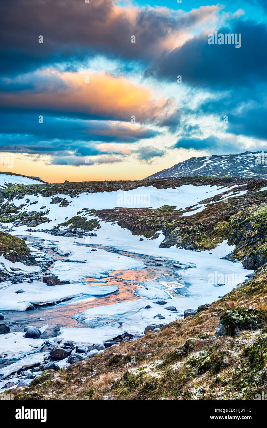 Une rivière gelée dans les hautes terres d'Islande encadrée par un ciel pastel et le terrain accidenté offre des paysages pittoresques illustrant le désert gelé. Banque D'Images