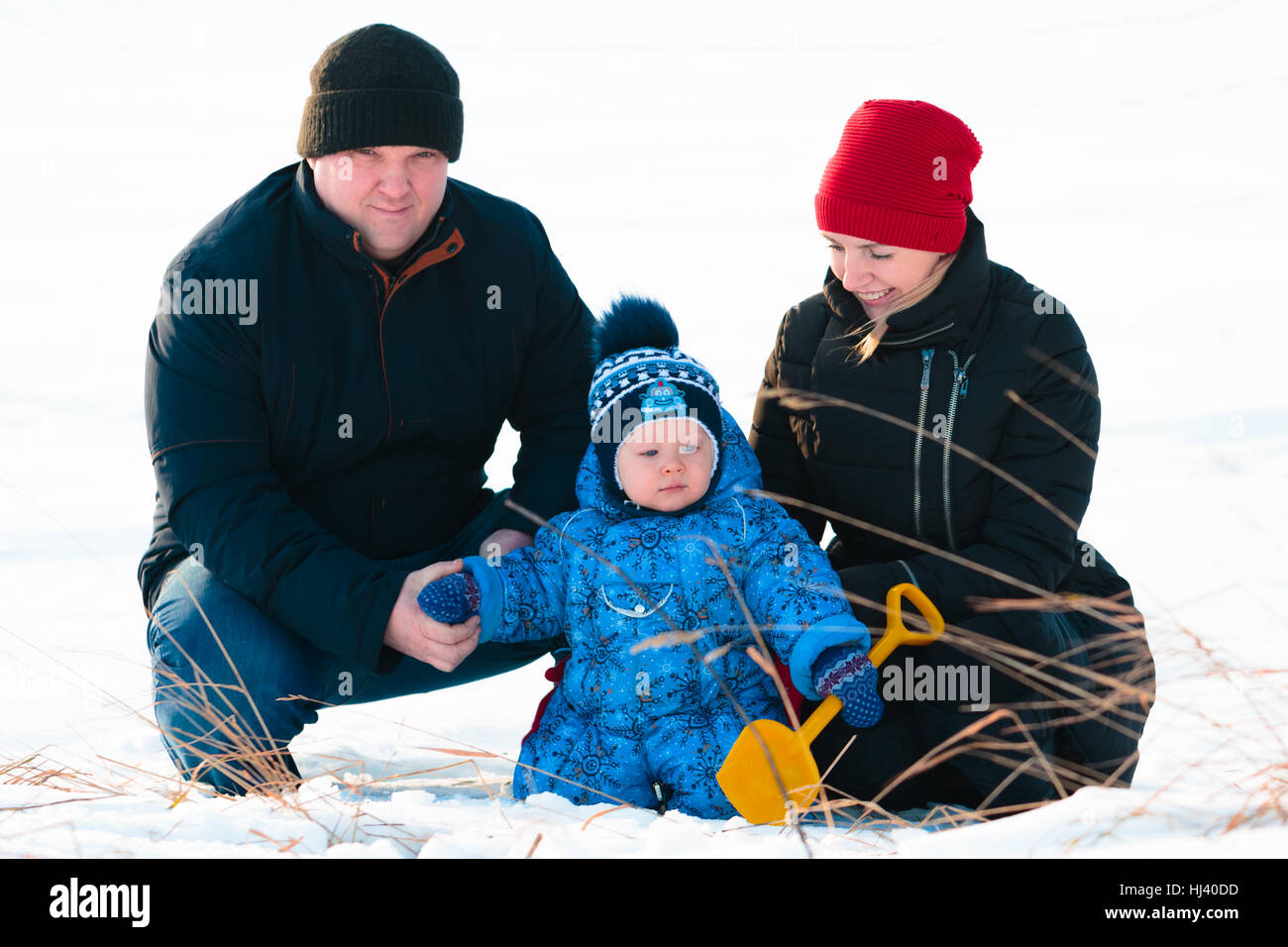 Famille de jouer avec leur enfant dans la neige dans le parc Banque D'Images