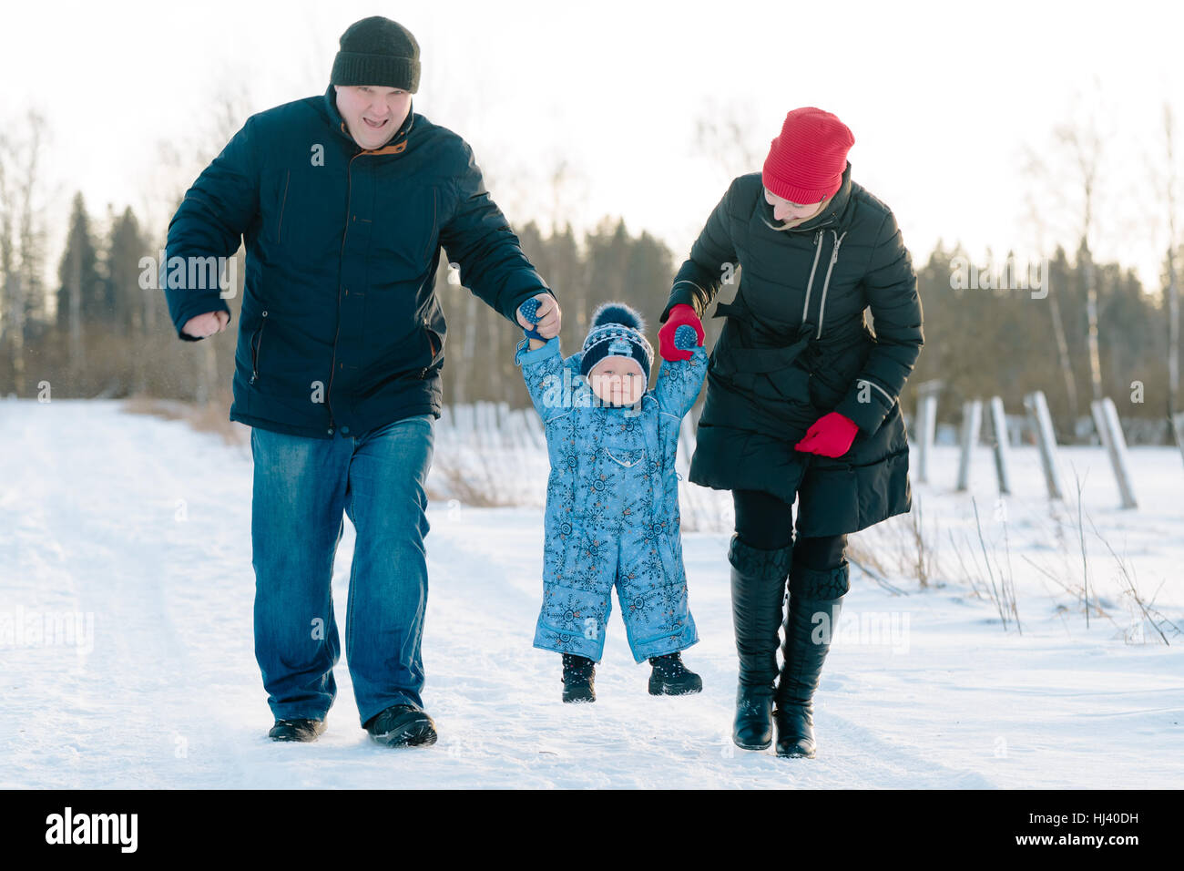 Maman et Papa Tenir mains du bébé à pied dans winter park Banque D'Images