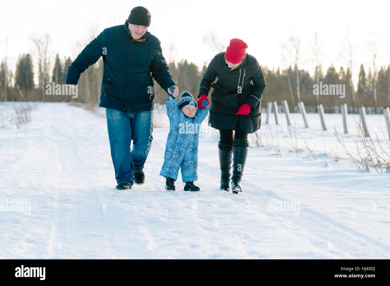 Maman et Papa Tenir mains du bébé à pied dans winter park Banque D'Images