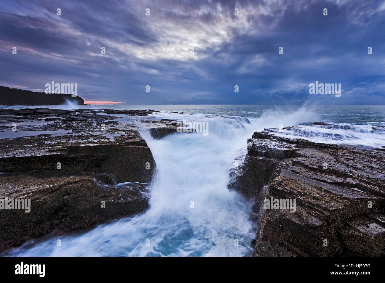 Côte sauvage de l'Australie Sydney plages du nord au lever du soleil, quand de fortes vagues de tempête a frappé la côte de rochers de grès crack Banque D'Images