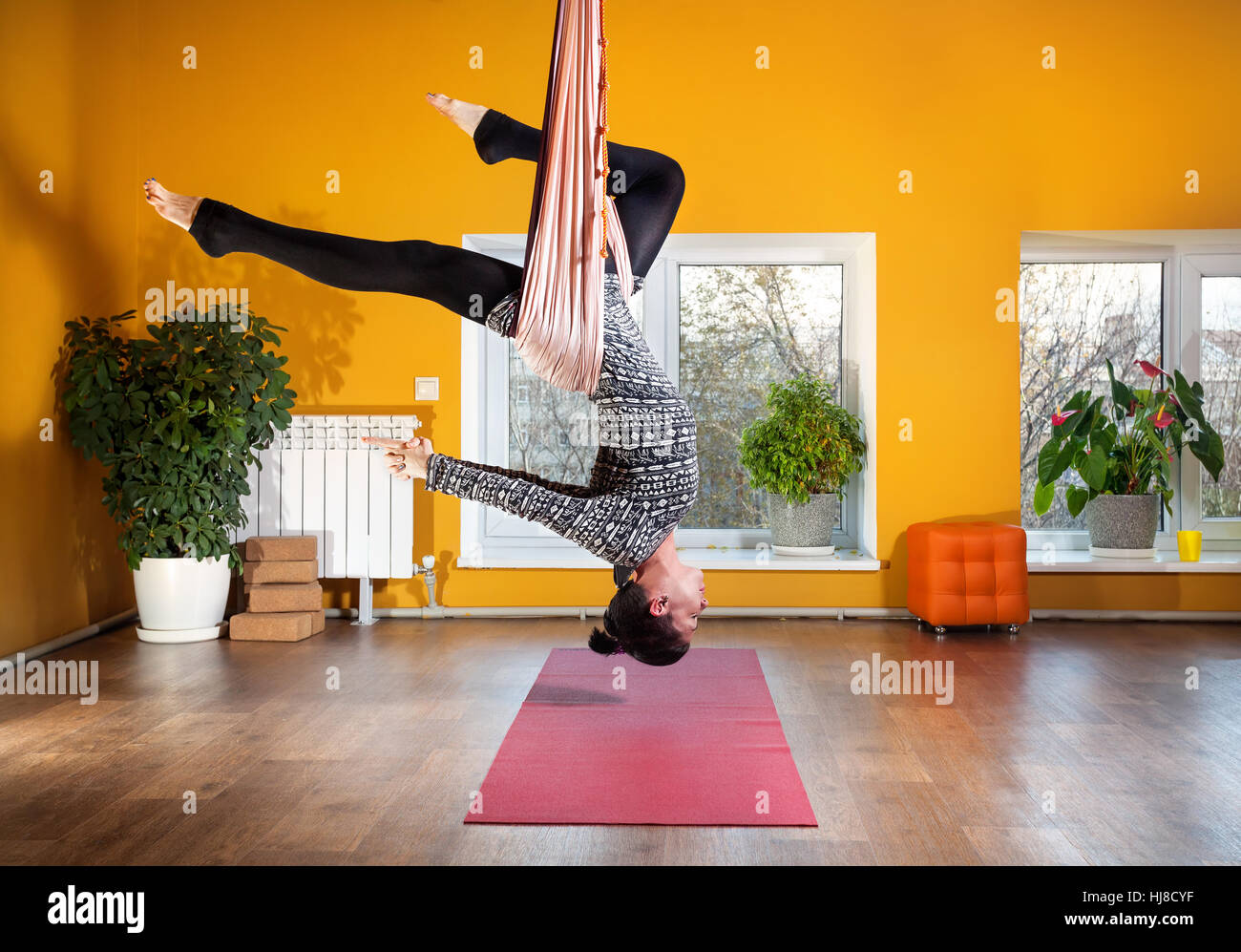 Young woman doing yoga anti-gravité au studio de bien-être avec des murs jaunes Banque D'Images