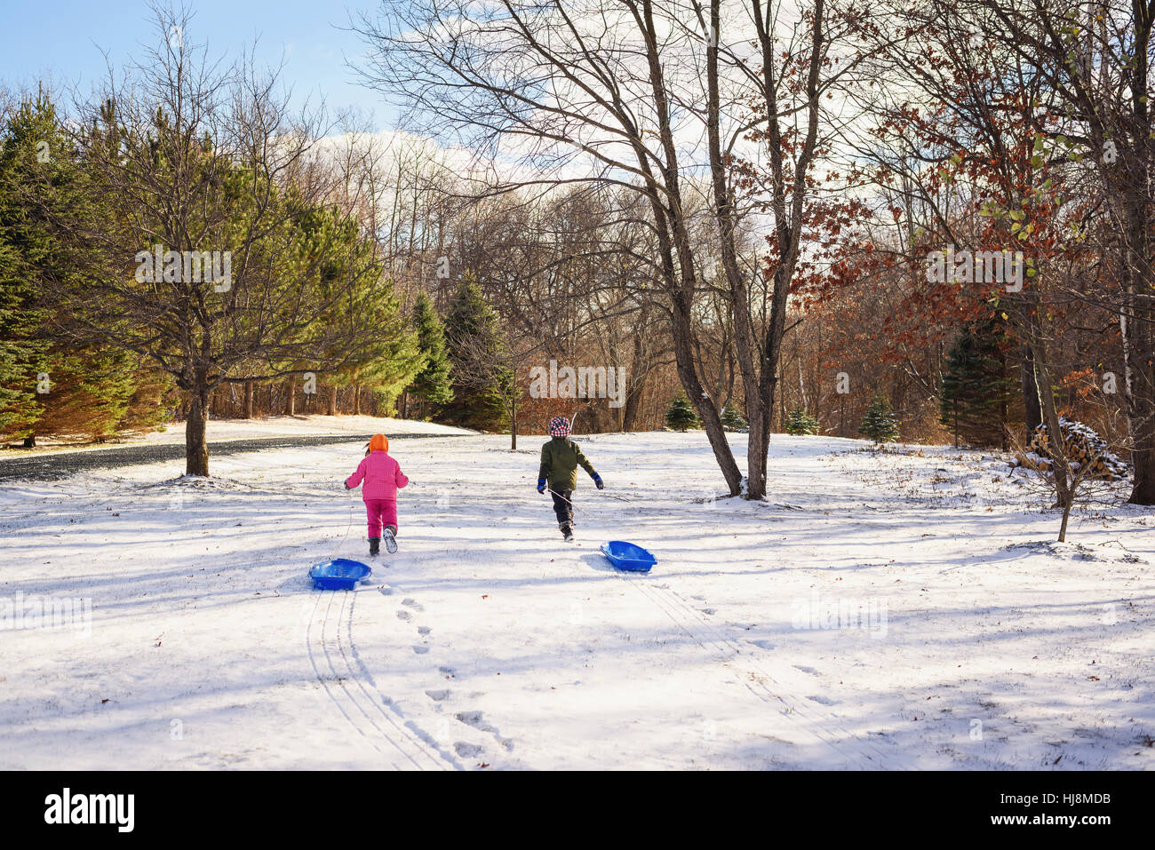 Deux enfants tirant des traîneaux dans la neige Banque D'Images