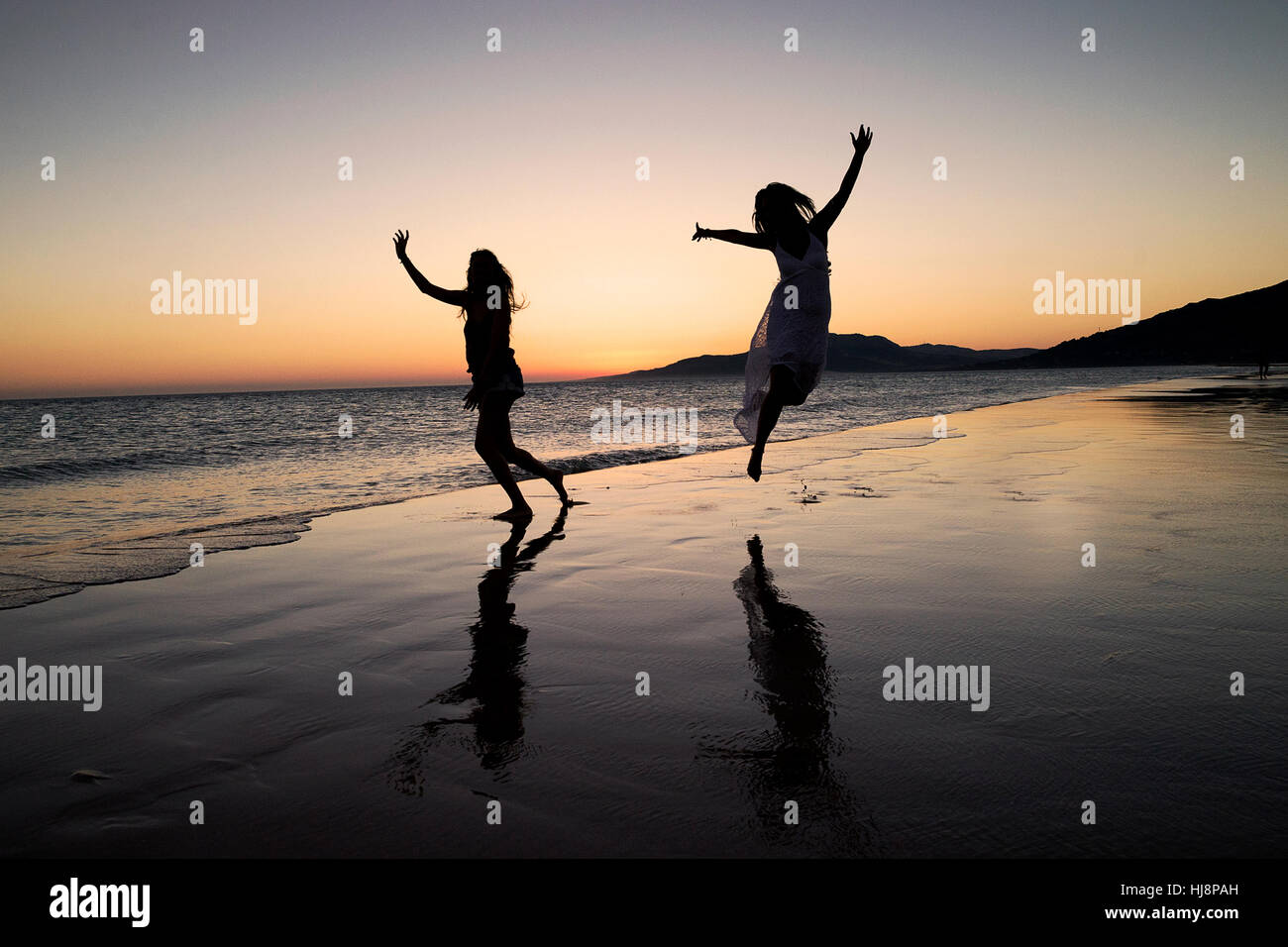 Silhouette de deux femmes dansant sur la plage de los Lances au coucher du soleil, Tarifa, Cadix, Andalousie, Espagne Banque D'Images