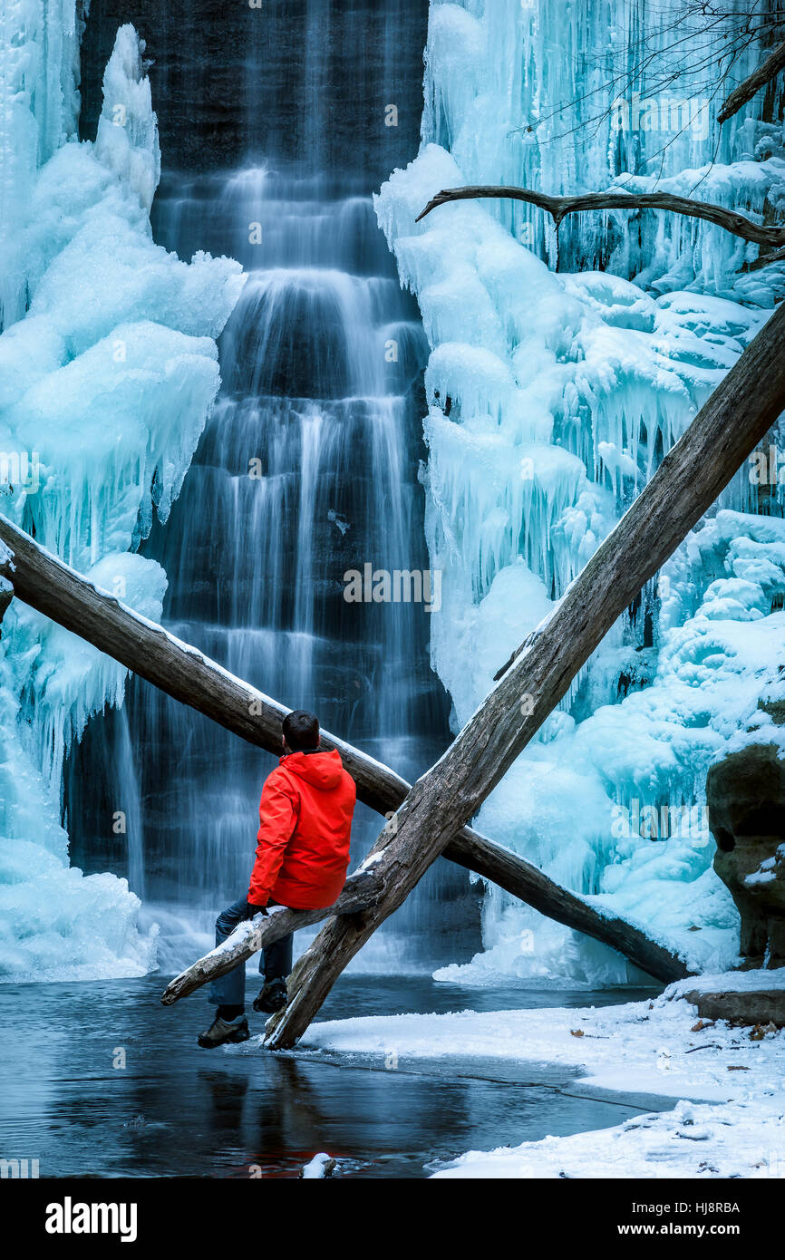 Homme assis près d'une chute d'eau gelée, Matthiessen State Park, Illinois, États-Unis Banque D'Images