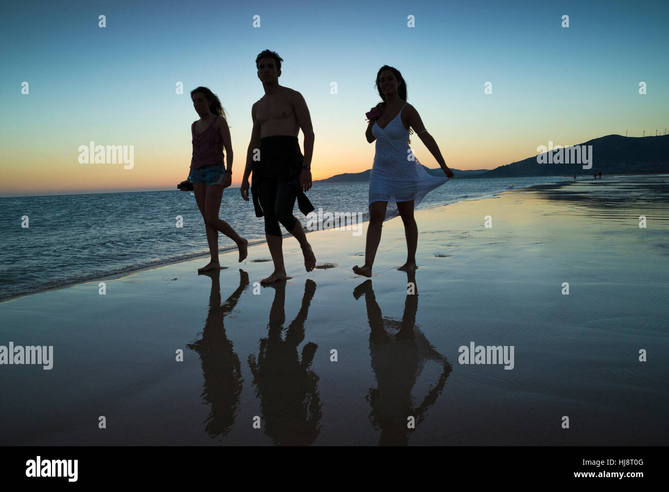 Silhouette de trois personnes marchant le long de plage au coucher du soleil, la plage de Los Lances, Tarifa, Cadix, Andalousie, Espagne Banque D'Images