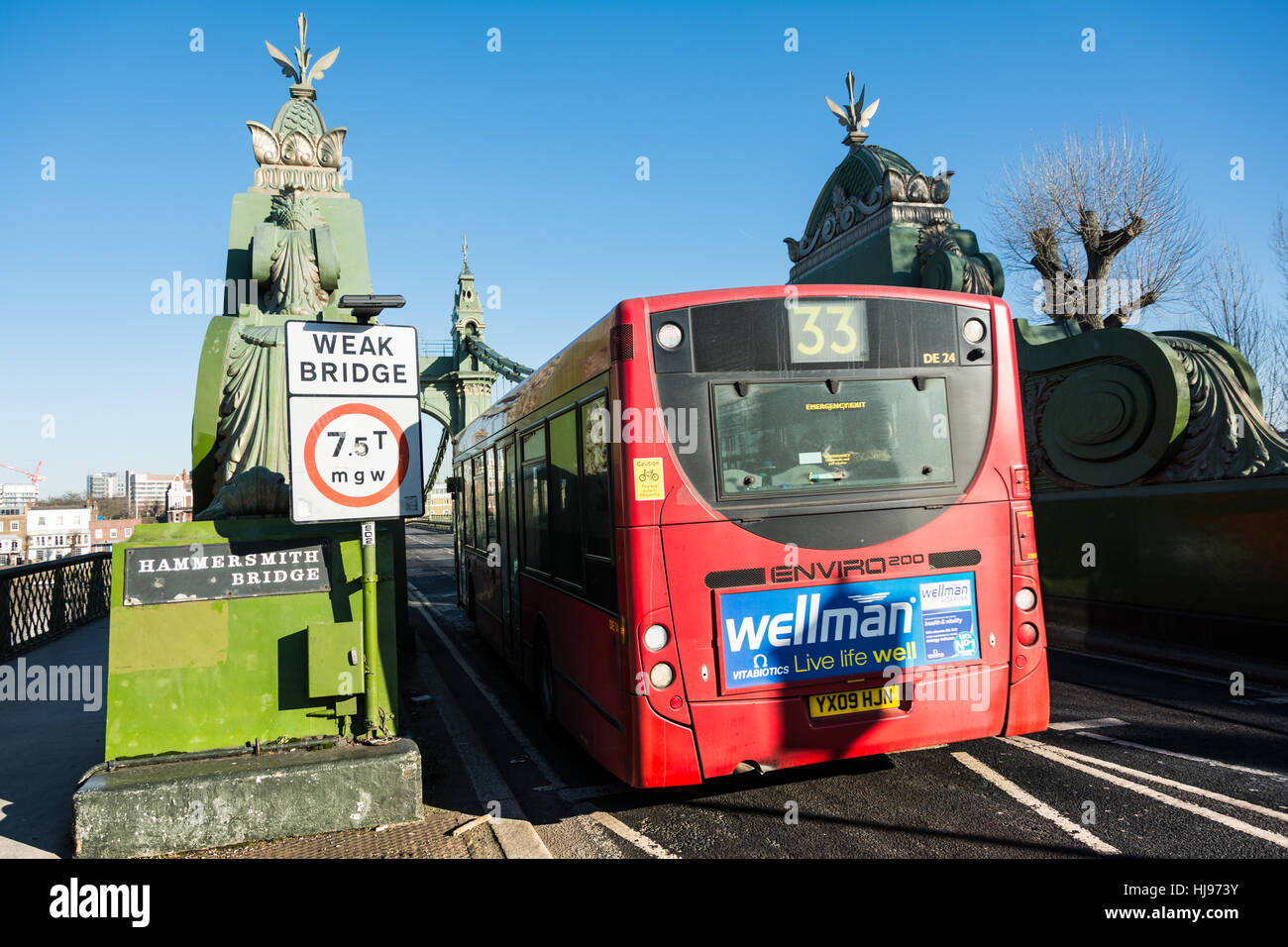 Un bus transport pour Londres 33 passant un signe de pont faible sur Hammersmith Bridge à l'ouest de Londres, Angleterre, Royaume-Uni. Banque D'Images