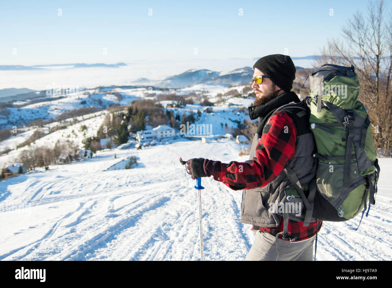 Backpacker barbu debout sur la montagne couverte de neige Banque D'Images