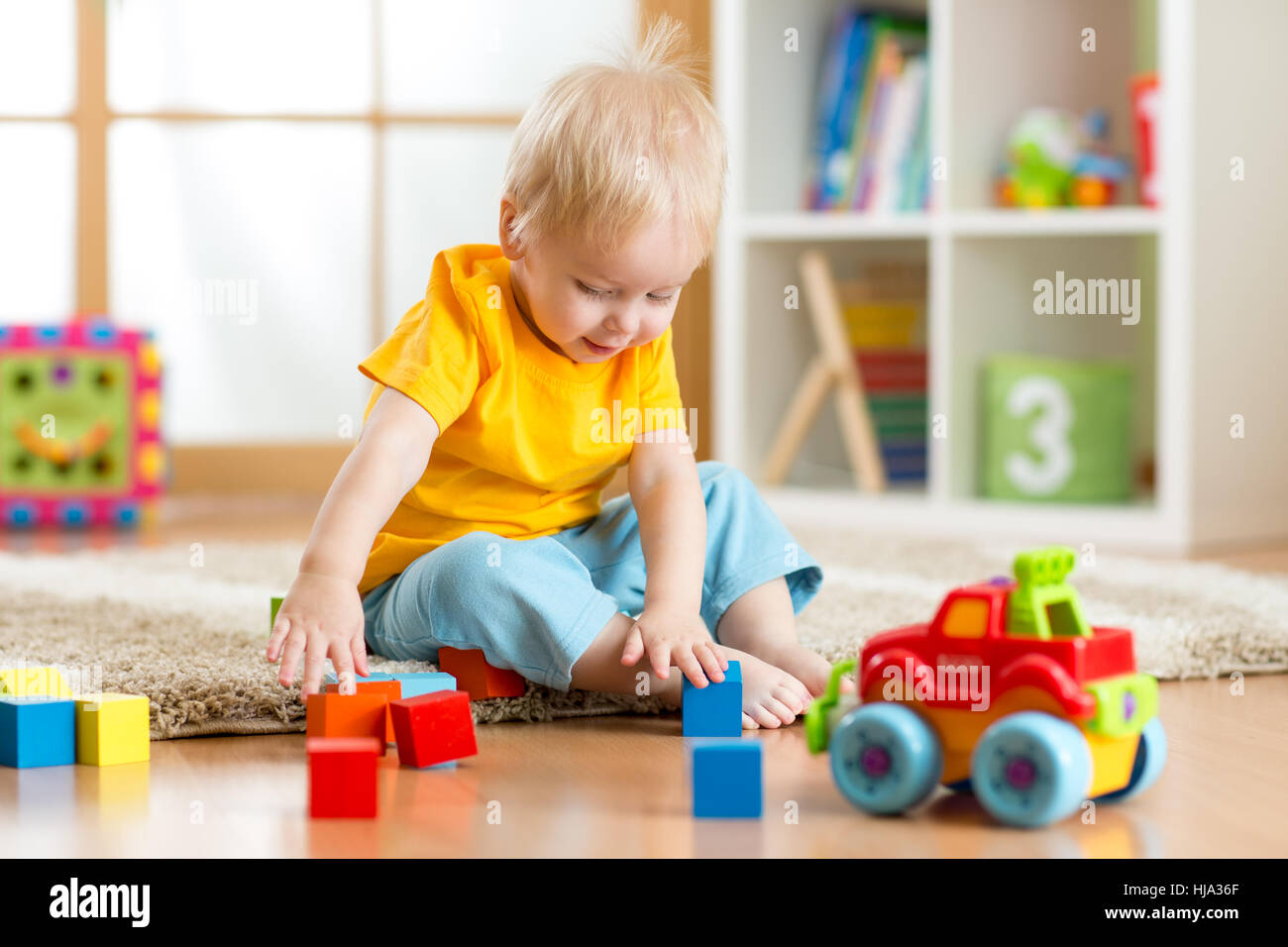 Kid toddler playing toy blocks dans sa chambre ou la crèche Banque D'Images