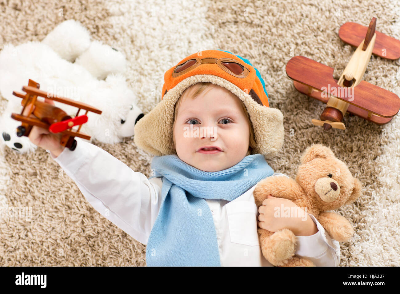 Happy child Playing with toy airplane. Kid garçon couché sur un tapis moelleux Banque D'Images