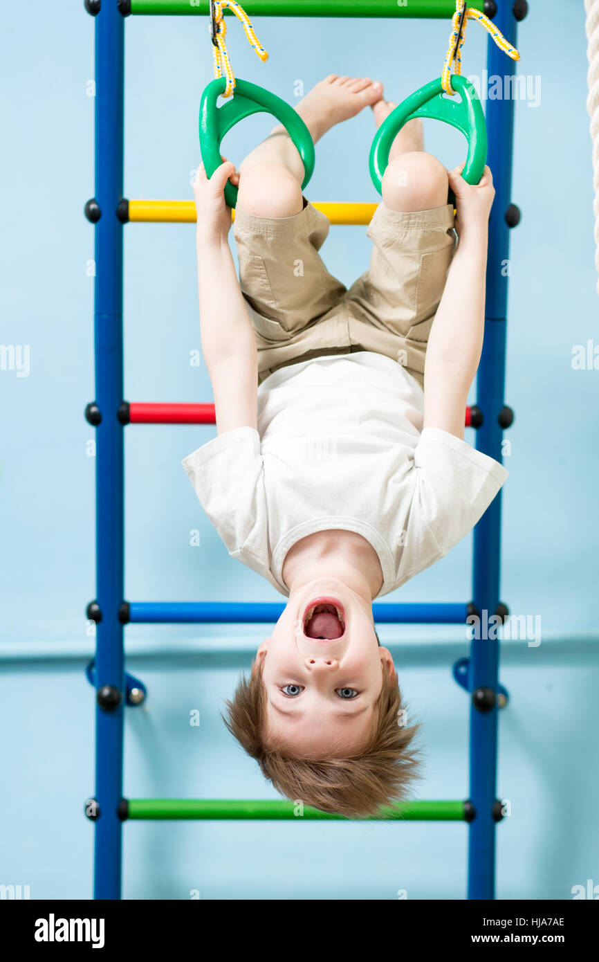 Kid garçon sur l'anneaux de gymnastique dans la salle de fitness class Banque D'Images