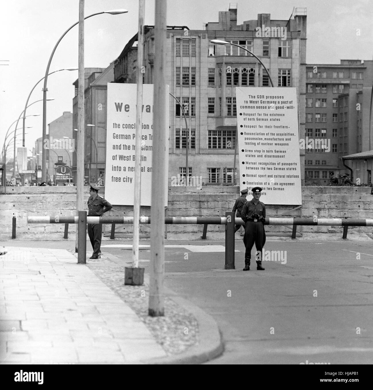 Barrière sur le mur de Berlin avec des pancartes de propagande "La RDA à l'Allemagne de l'Ouest propose un pacte de bon sens et de bonne volonté', tandis que la photo nous président JFK était sur son chemin à un point de vue sur le mur de Berlin près de Checkpoint Charlie se trouvent à proximité. Banque D'Images