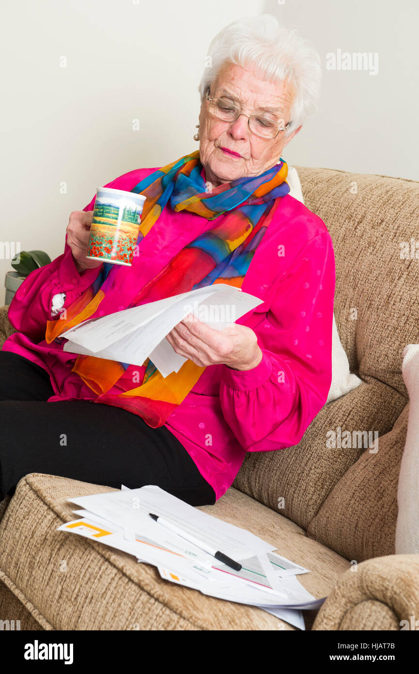 Une dame plus âgée organiser son outgoings mensuels à son domicile dans un effort pour économiser de l'argent Banque D'Images