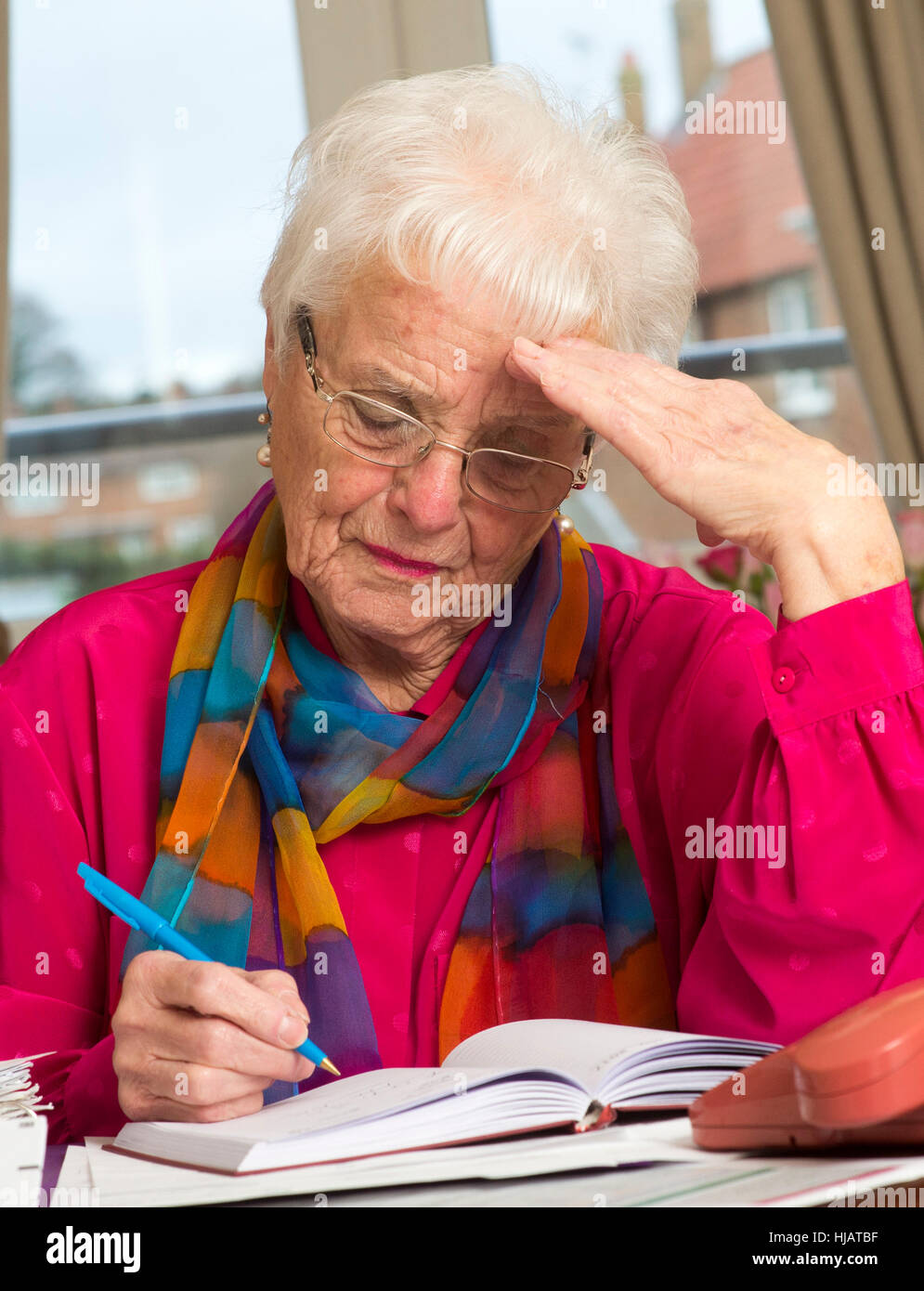 Une dame plus âgée organiser son outgoings mensuels à son domicile dans un effort pour économiser de l'argent Banque D'Images