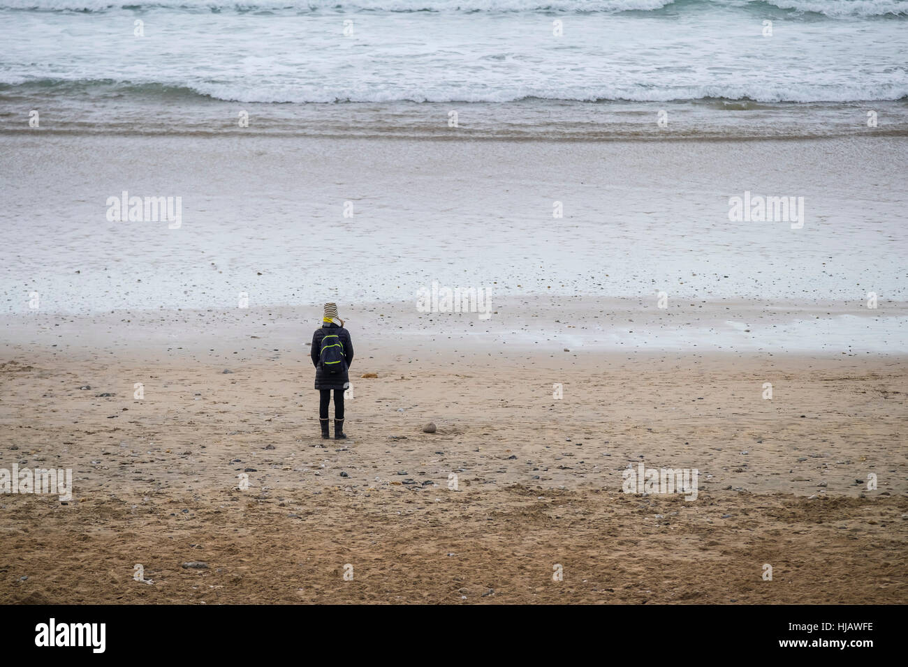 Une femme debout seul sur la plage de Fistral, Newquay, Cornwall, England, UK. Banque D'Images