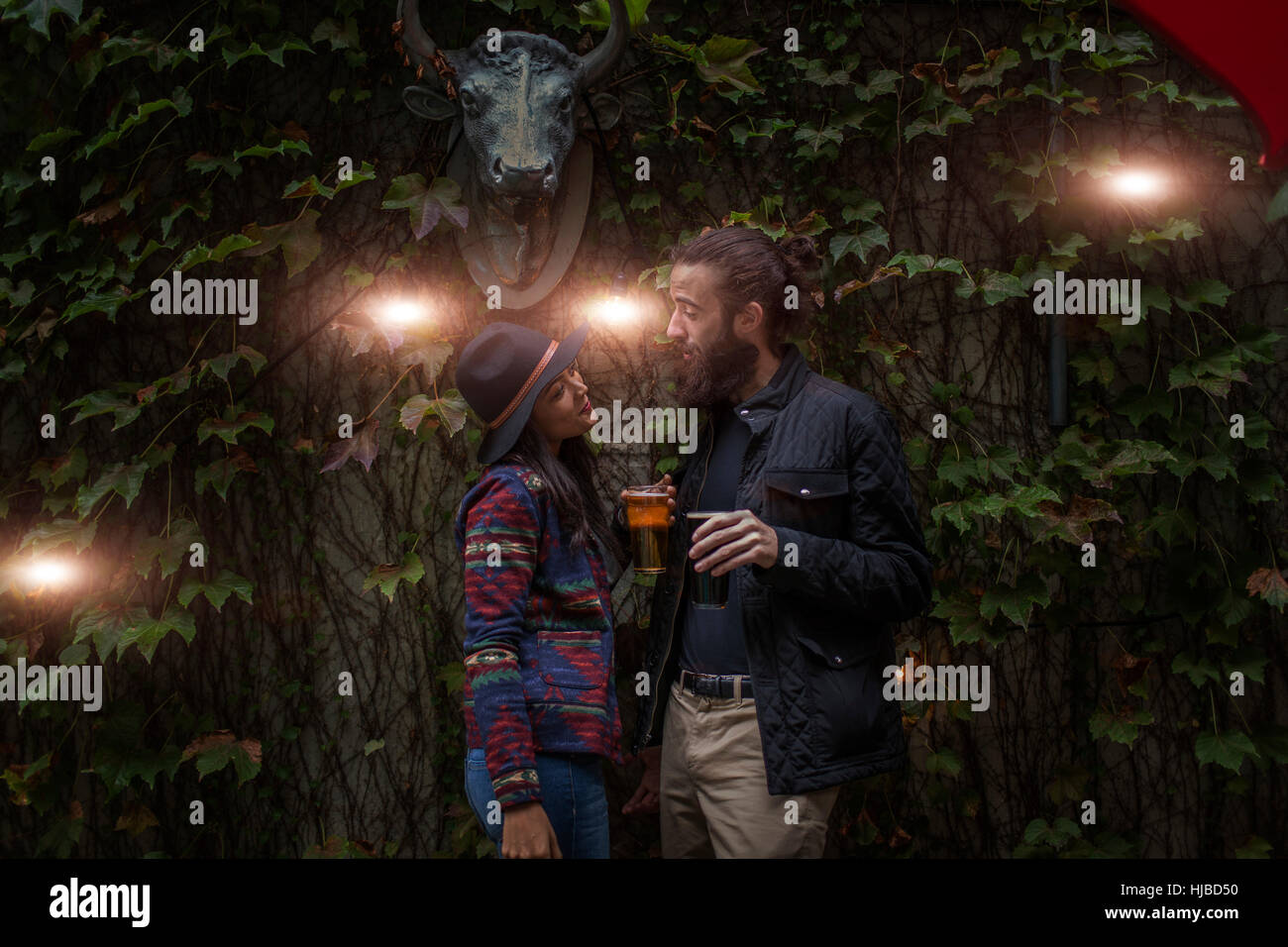 Jeune couple en pleine discussion dans le jardin de la bière en soirée, Brooklyn, New York, USA Banque D'Images