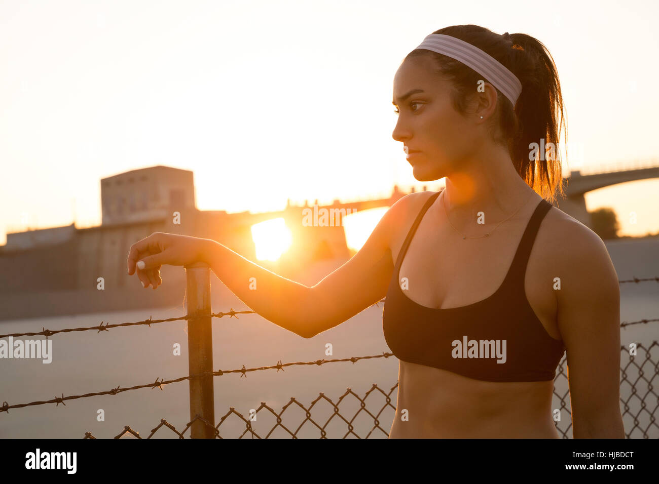 La rêverie de l'athlète féminine par grillage au coucher du soleil, Van Nuys, Californie, USA Banque D'Images