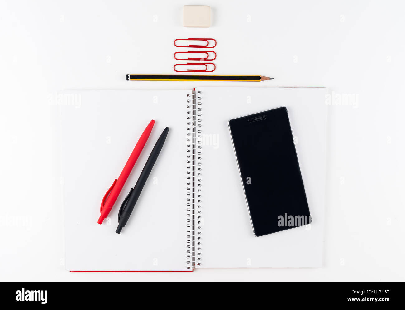 Espace de bureau sur fond blanc avec le smartphone. Ordinateur portable blanc avec crayon, stylo et clips. L'espace de copie de texte ou l'image Banque D'Images