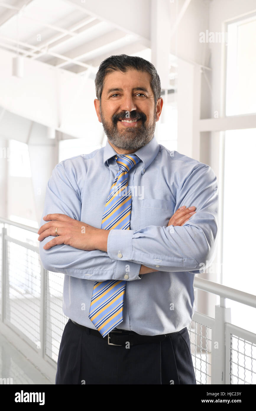 Senior Hispanic businessman smiling with arms crossed intérieur office building Banque D'Images