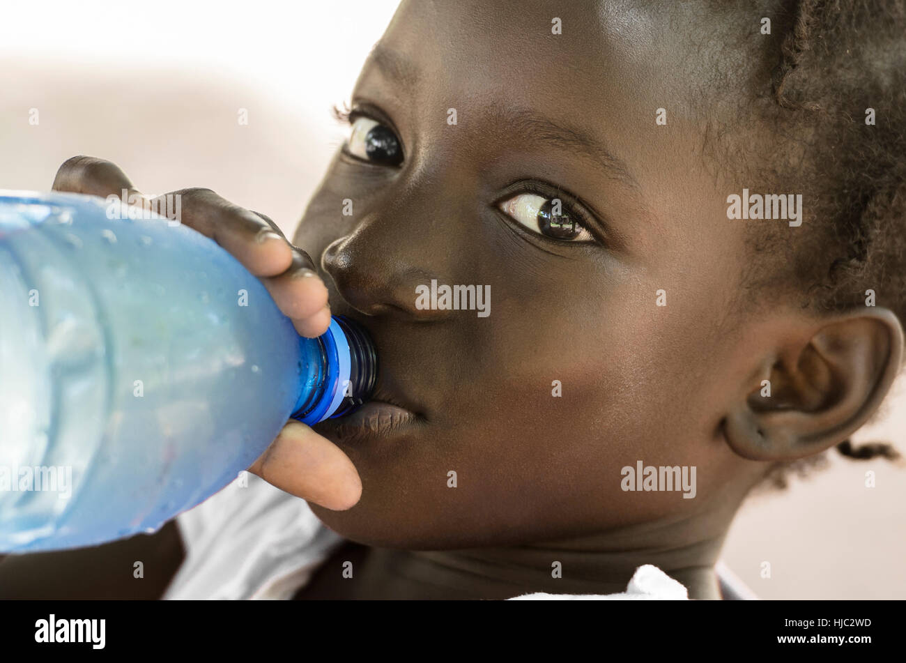 Symbole de la pauvreté : fille noire africaine saine potable l'eau douce. Symbole de la pauvreté au Mali : Black Girl africaine saine potable l'eau douce à partir d'une bouteille. Banque D'Images