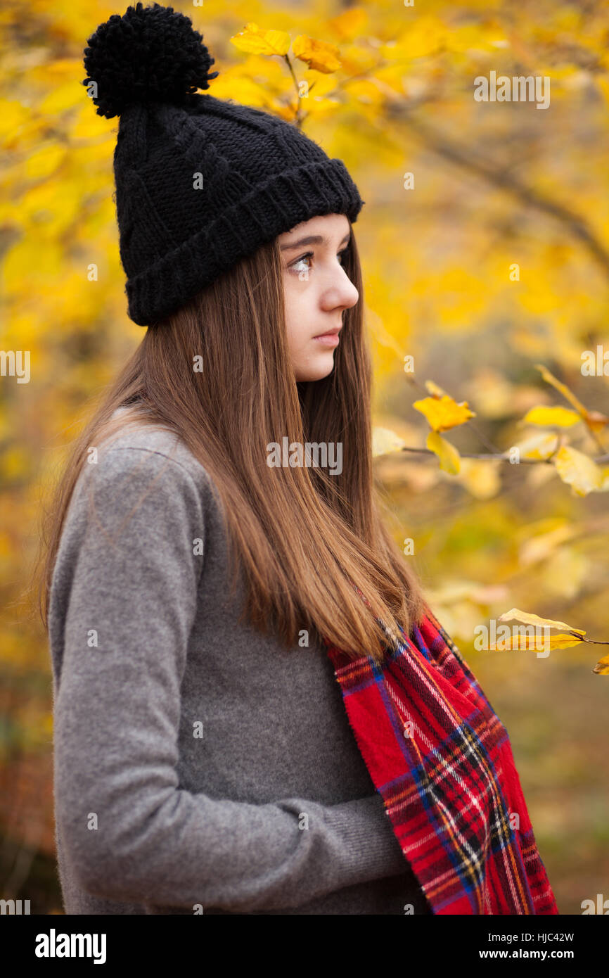Profil d'une jolie adolescente portant bonnet de laine avec des couleurs automnales en arrière-plan Banque D'Images