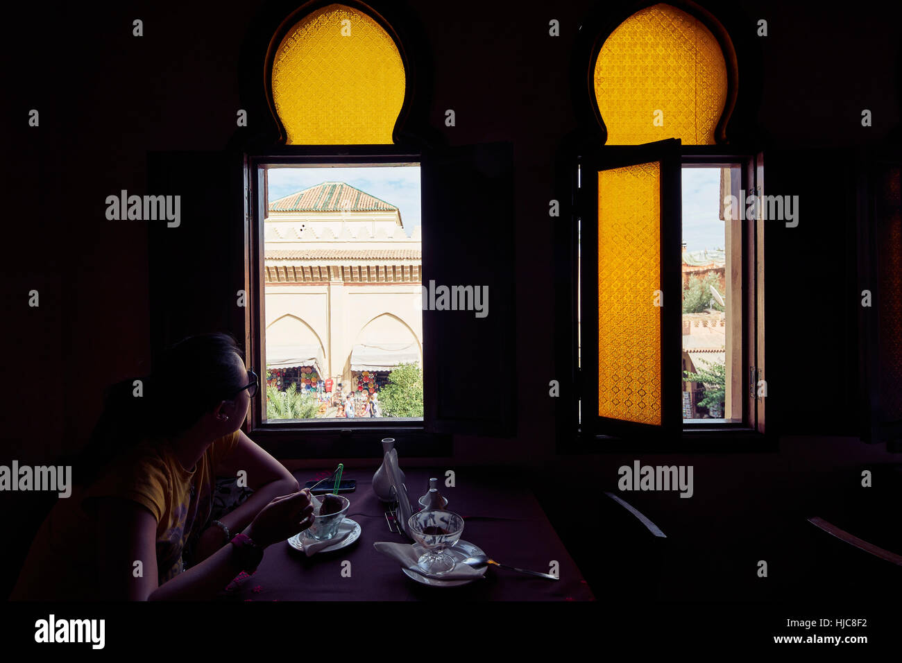 Woman eating dessert et regarder à travers la fenêtre restaurant, Marrakech, Maroc Banque D'Images