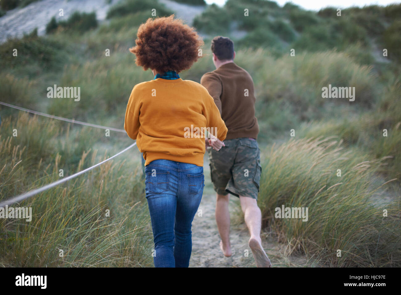 Couple running on grassy dune Banque D'Images