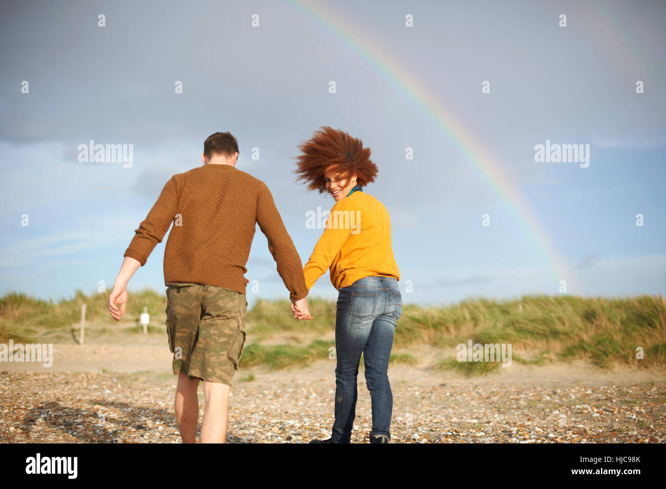 Couple walking on beach vers rainbow Banque D'Images