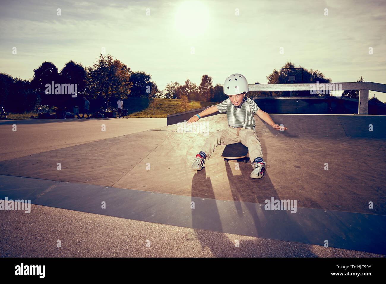 Garçon assis sur roulettes dans park Banque D'Images