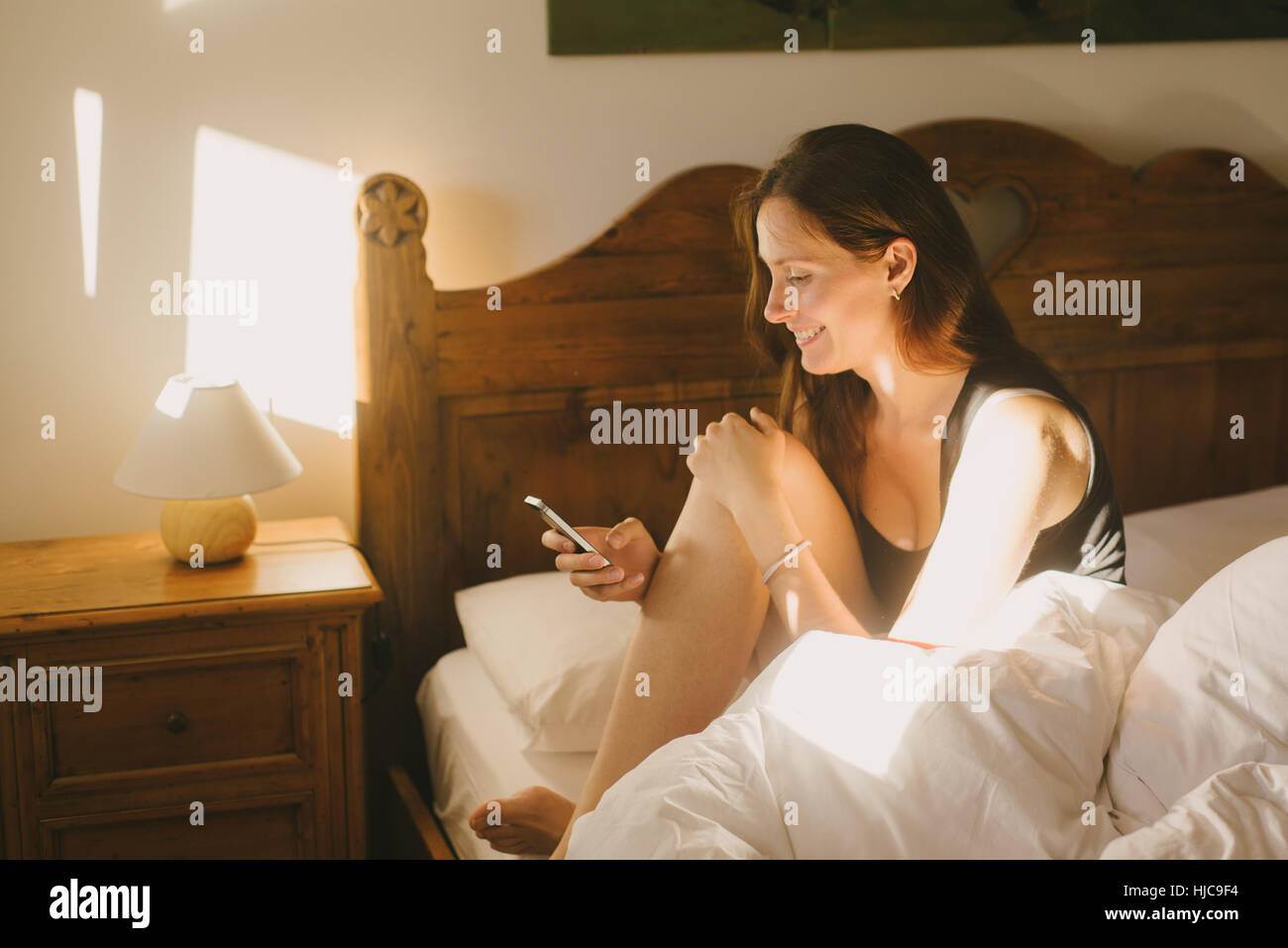 Woman using mobile phone in bed Banque D'Images