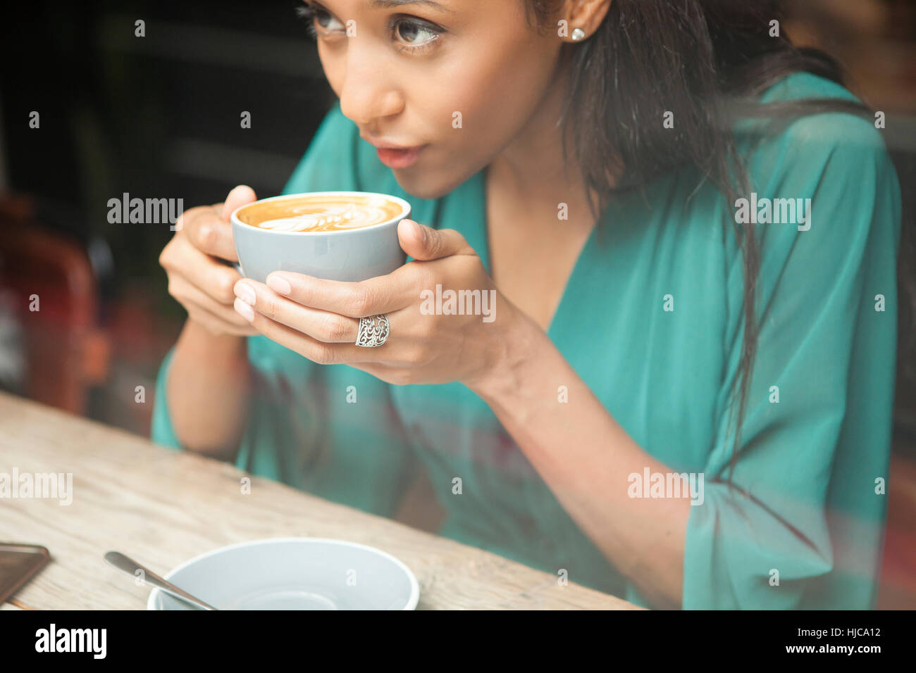 Mid adult woman holding Coffee cup à la fenêtre de cafe Banque D'Images