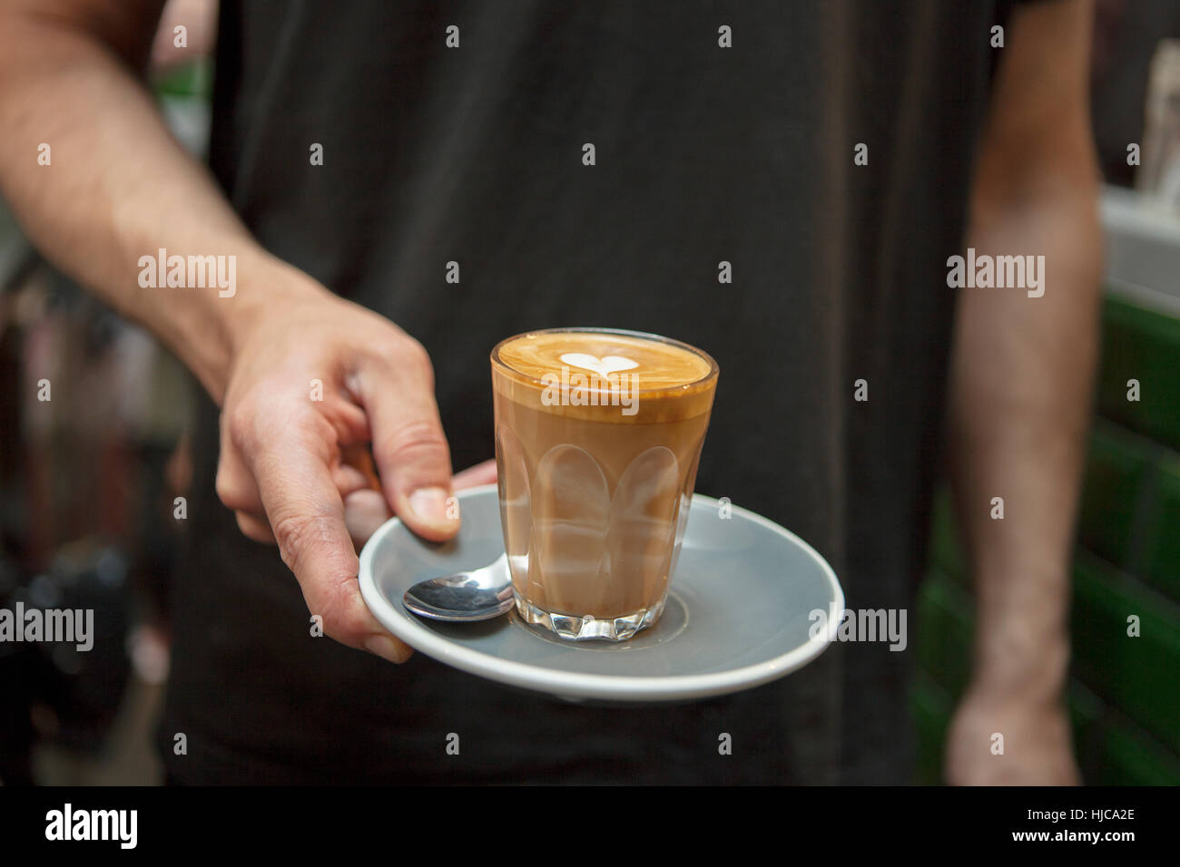 Cropped shot de barista holding glass of coffee in cafe Banque D'Images