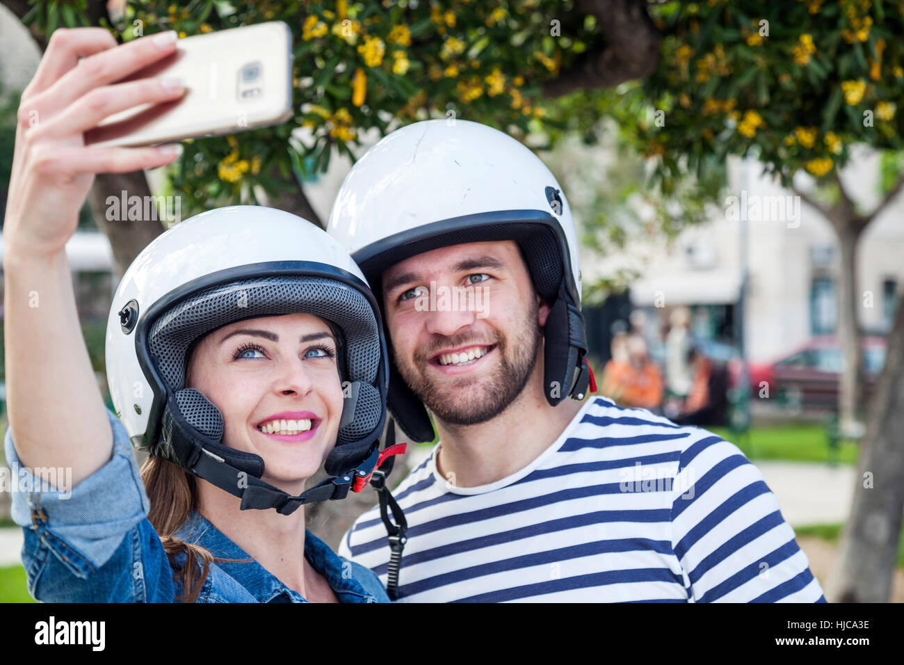 Jeune couple de cyclomoteurs en tenant en selfies park, Split, Dalmatie, Croatie Banque D'Images