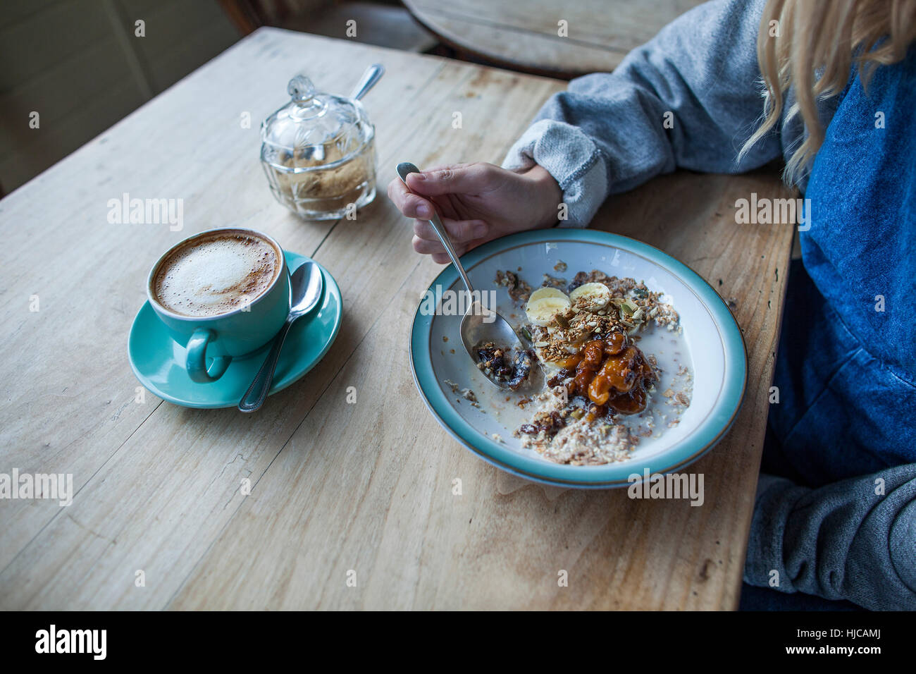 Young woman in cafe, manger du muesli, mid section Banque D'Images