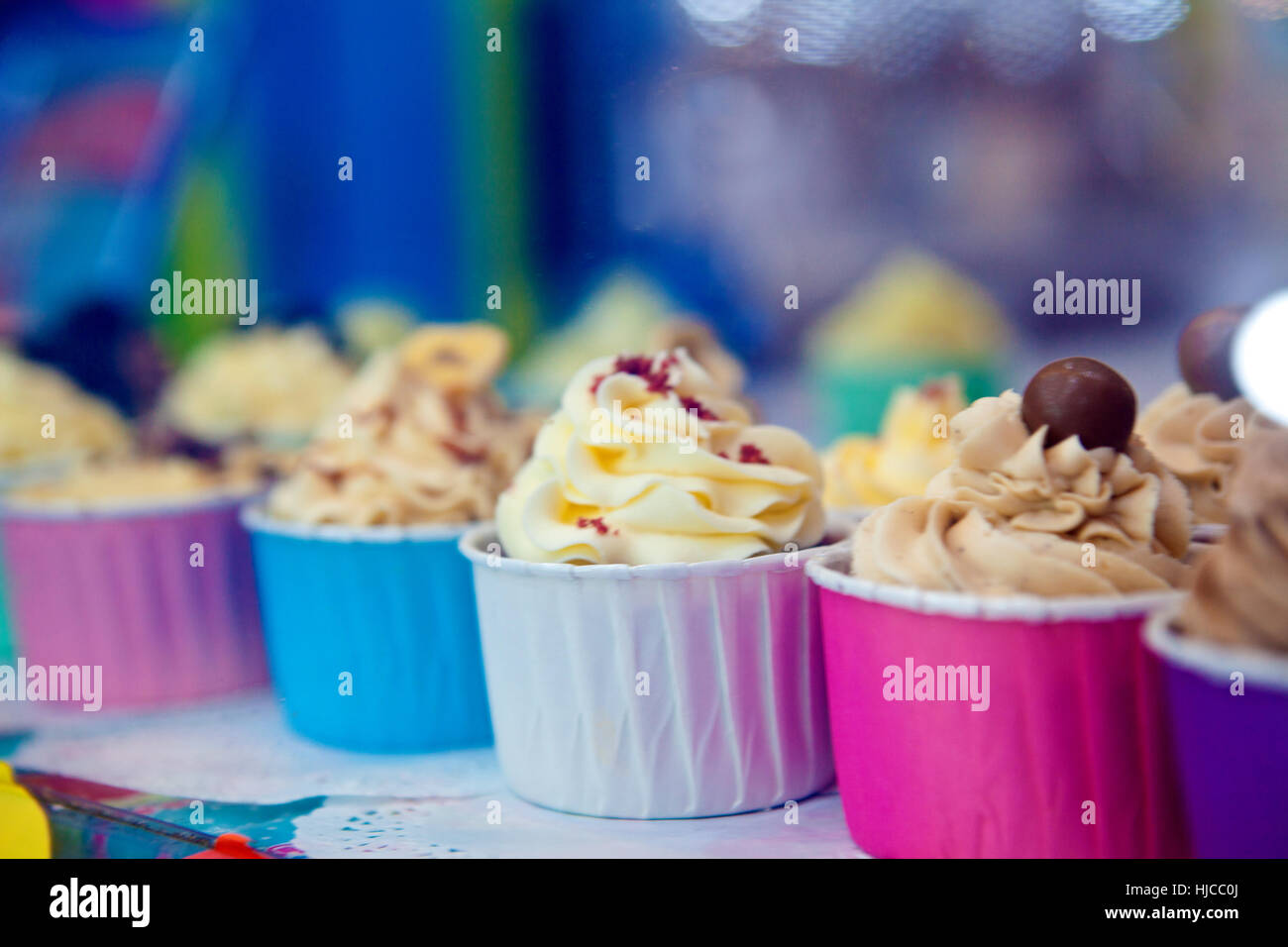 Rangée de cupcakes colorés avec du glaçage en vitrine Banque D'Images