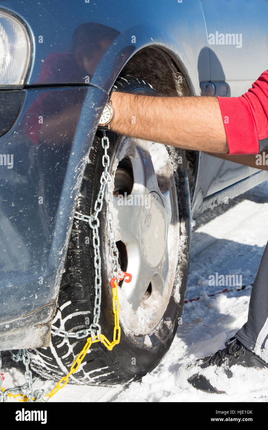 Montage de chaînes à neige homme sur les roues de voiture Banque D'Images