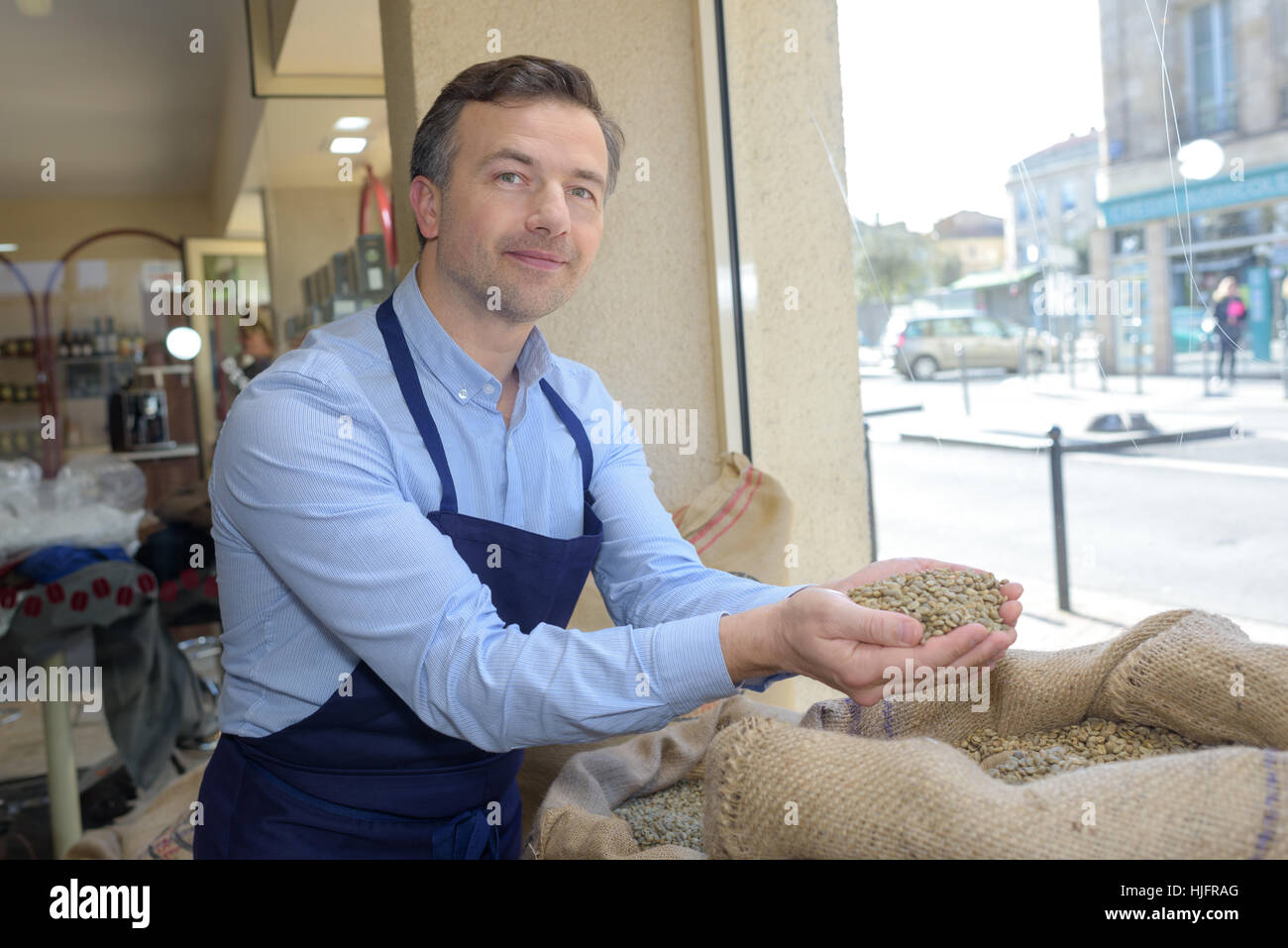Vendeur qui détient une écope d'un grain de café torréfié brun Banque D'Images