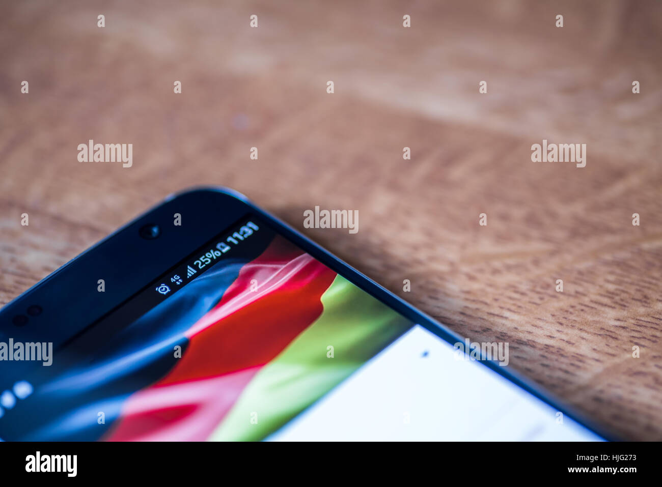 Smartphone sur fond de bois avec 4G Réseau inscription 25  % et drapeau allemand sur l'écran. Banque D'Images
