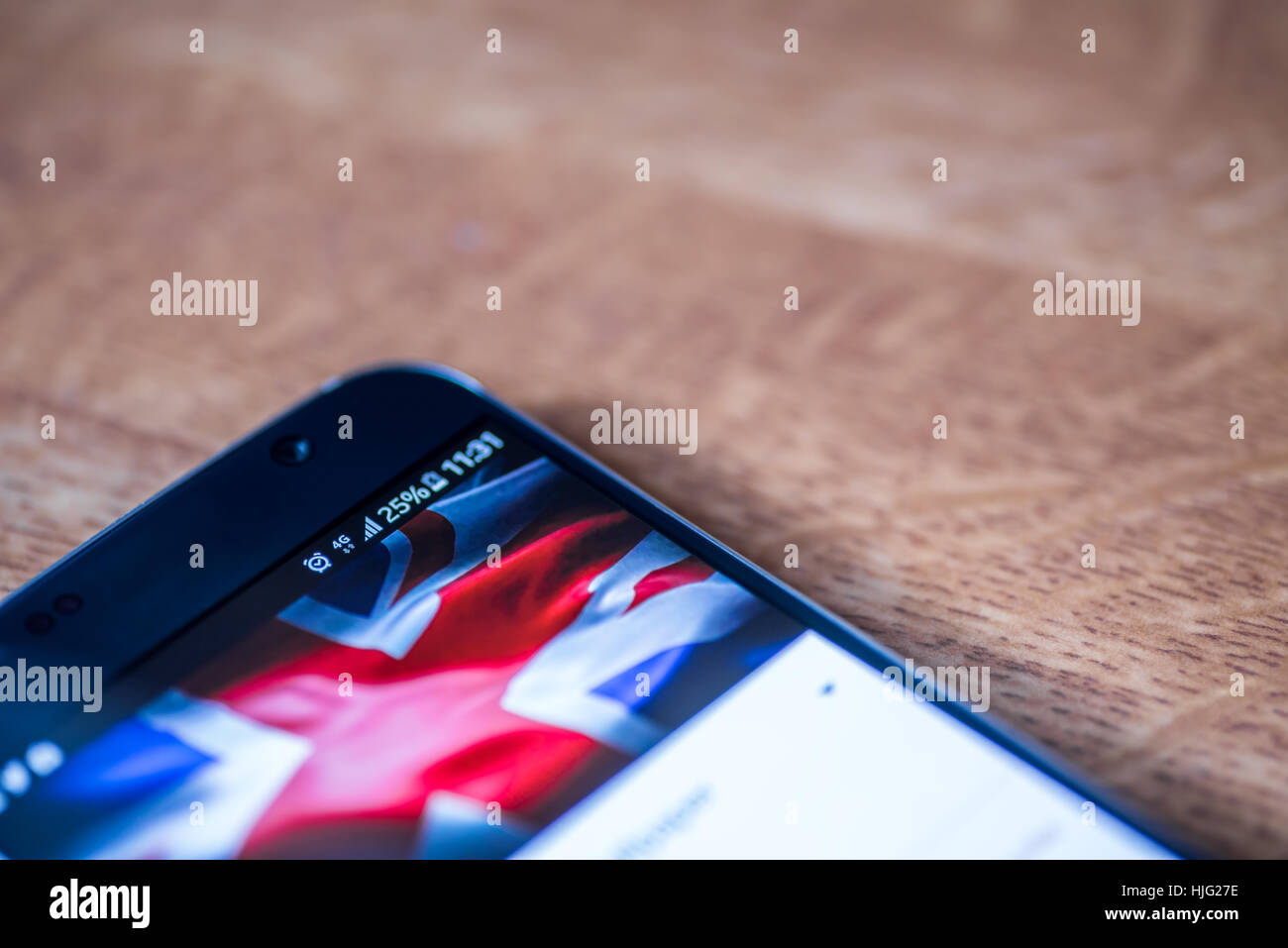 Smartphone sur fond de bois avec 4G Réseau inscription 25  % et UK drapeau sur l'écran. Banque D'Images