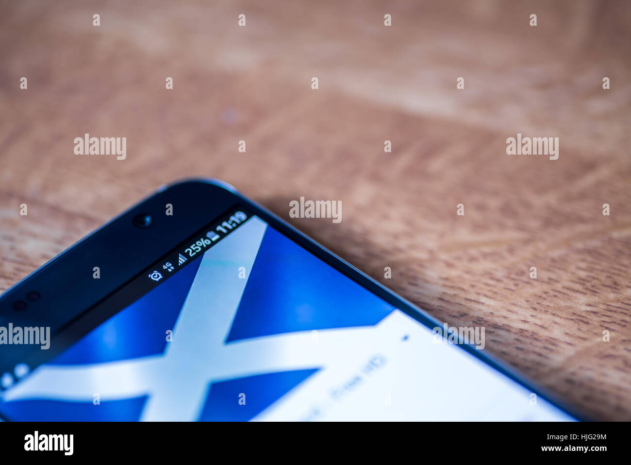 Smartphone sur fond de bois avec 4G Réseau inscription 25  % et de l'Écosse drapeau sur l'écran. Banque D'Images